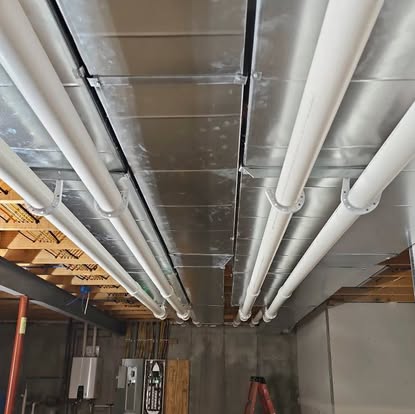 Overhead pipes and ductwork in a basement, from Williams Heating & Cooling